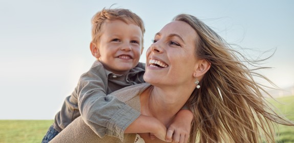 Mutter mit Kind Huckepack auf Wiese